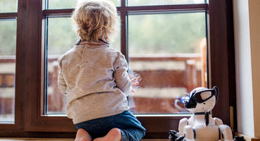 Roboter-Hund steht neben einem Jungen am Fenster