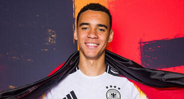 Jamal Musiala posiert mit Deutschland-Flagge in seinem EM-Trikot.