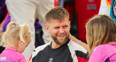 Niclas Füllkrug lachend in der Mitte, links seine Tochter Emilia, rechts seine Ehefrau Lisa, alle tragen Deutschland Trikots