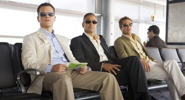 Matt Damon, George Clooney und Brad Pitt sitzen in "Ocean's 13" am Flughafen und blicken in die Ferne