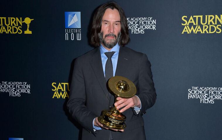 Keanu Reeves auf dem roten Teppich mit Preis in der Hand 