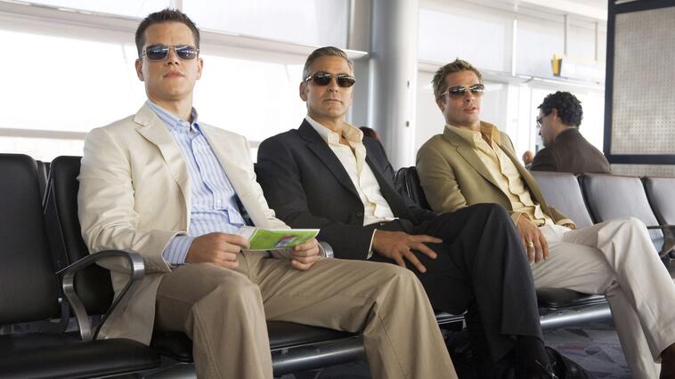 Matt Damon, George Clooney und Brad Pitt sitzen in "Ocean's 13" am Flughafen und blicken in die Ferne