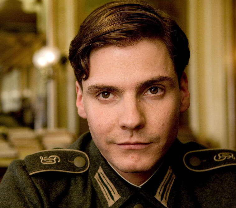 Daniel Brühl schaut bei einem Film in die Kamera und hat eine alte Uniform an