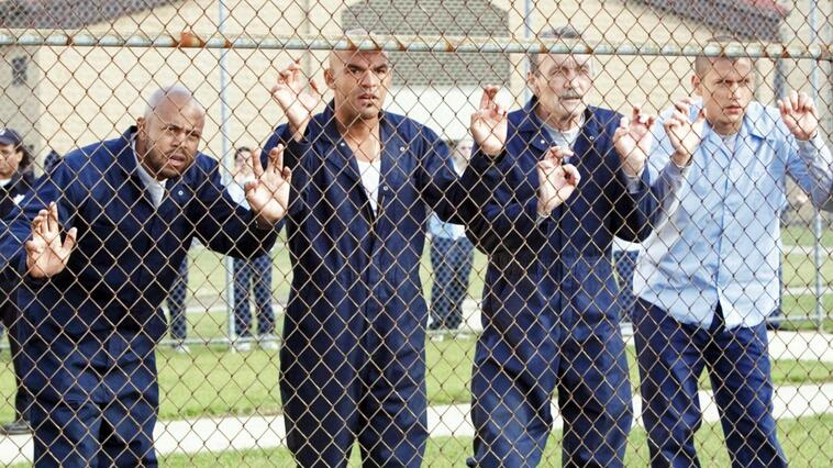 Die Figuren aus "Prison Break" Staffel 1 stehen an einem Machendrahtzaun